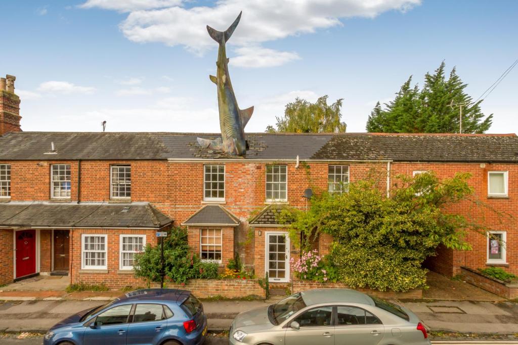 two cars parked in front of a brick building with a statue at The Headington Shark House - Oxford in Oxford