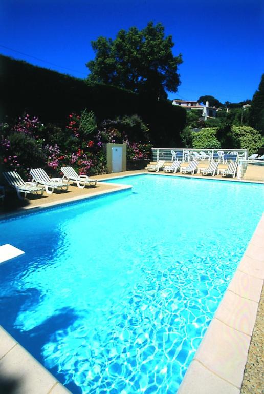 a swimming pool with chairs and a swimming pool at Hôtel Lou Paouvadou in Sainte-Maxime