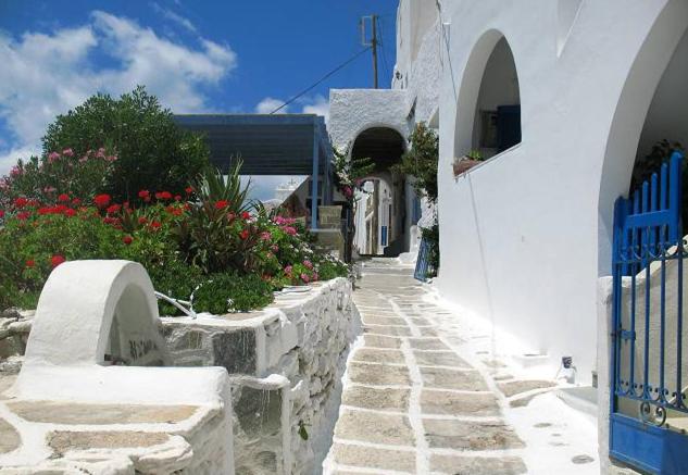 una calle con edificios blancos y un camino con flores en Vesuvio Chora, en Ios Chora