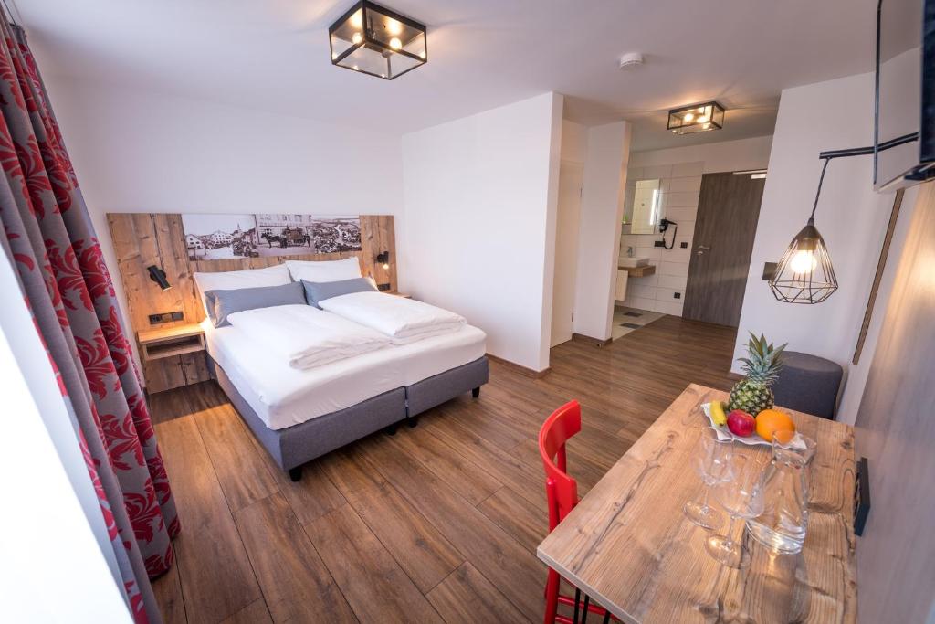 
a room with a bed, a table, and a dresser at Hotel & Brauerei-Gasthof Neuwirt in Neuburg an der Donau
