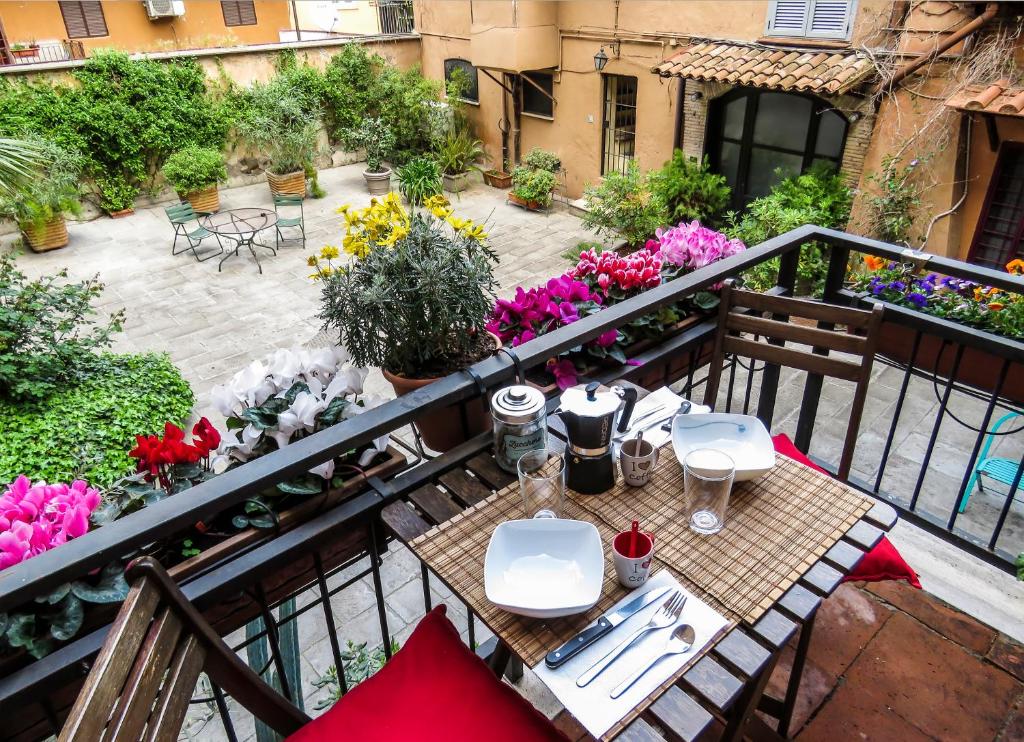 un balcone con tavolo, sedie e fiori di Casa del Moro - romantic loft in Trastevere a Roma