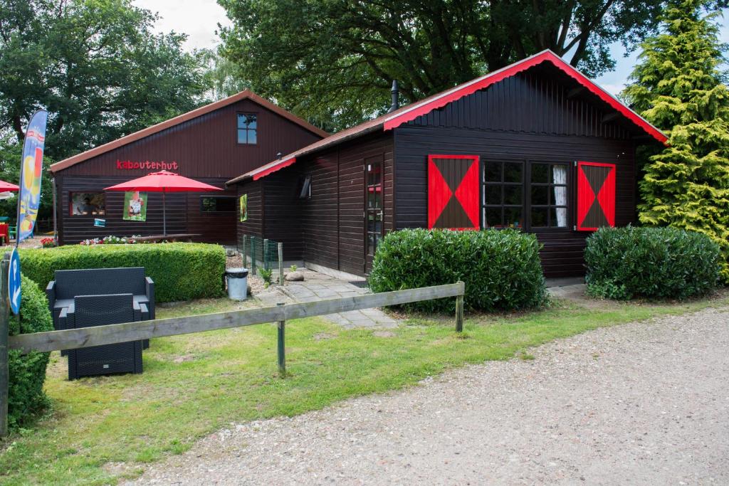 a cabin with red doors and a fence in front of it at rijk der kabouters in Eext