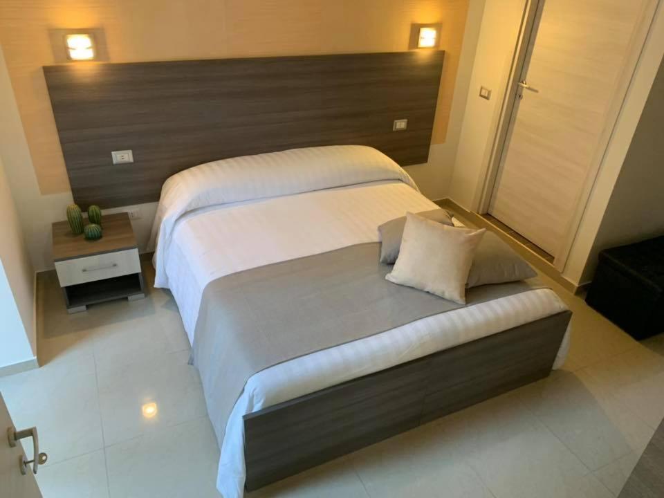 una camera con un grande letto con testiera in legno di Sweet Home a Francavilla di Sicilia