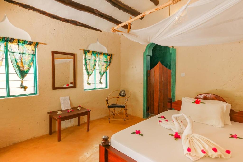 a bedroom with two beds and a table and windows at Demani Lodge Zanzibar in Paje