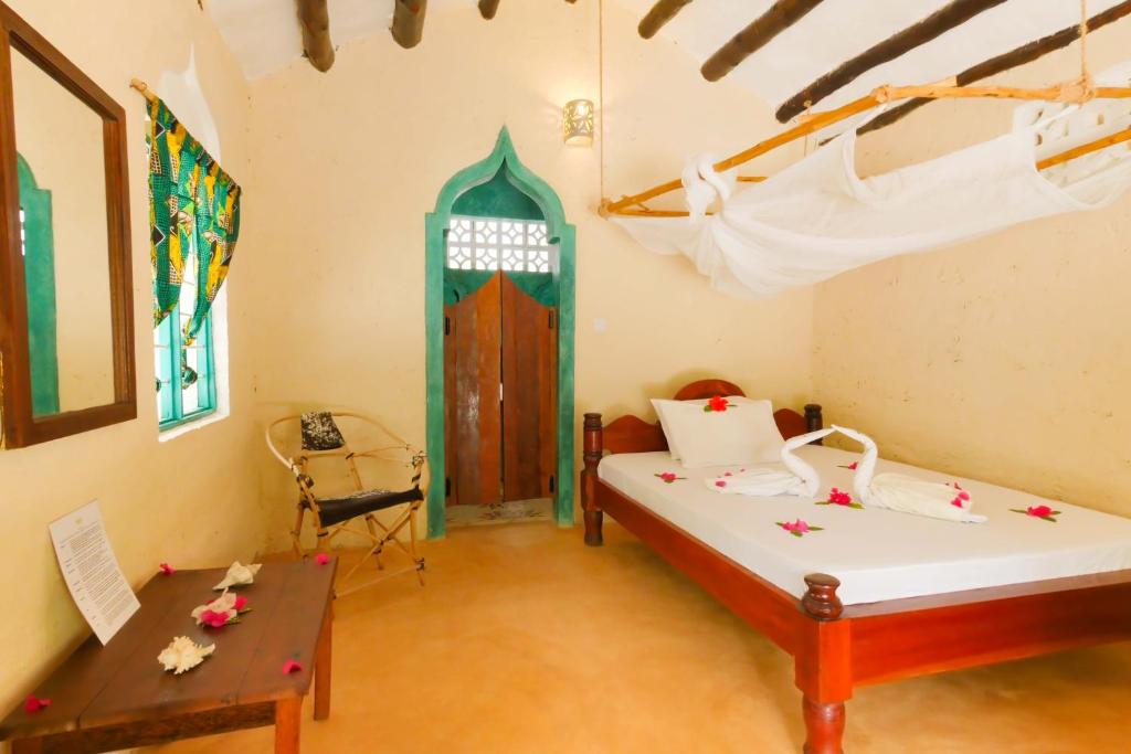 a bedroom with a bed and a table in a room at Demani Lodge Zanzibar in Paje
