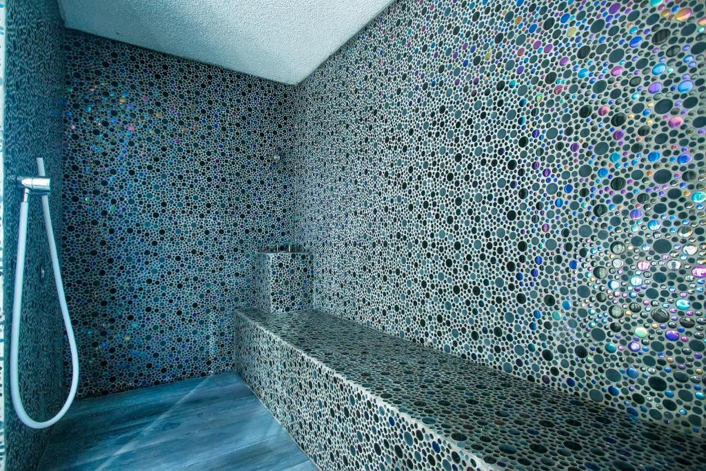 a bathroom with a shower with a mosaic wall at Hotel Lava Beach in Puerto del Carmen
