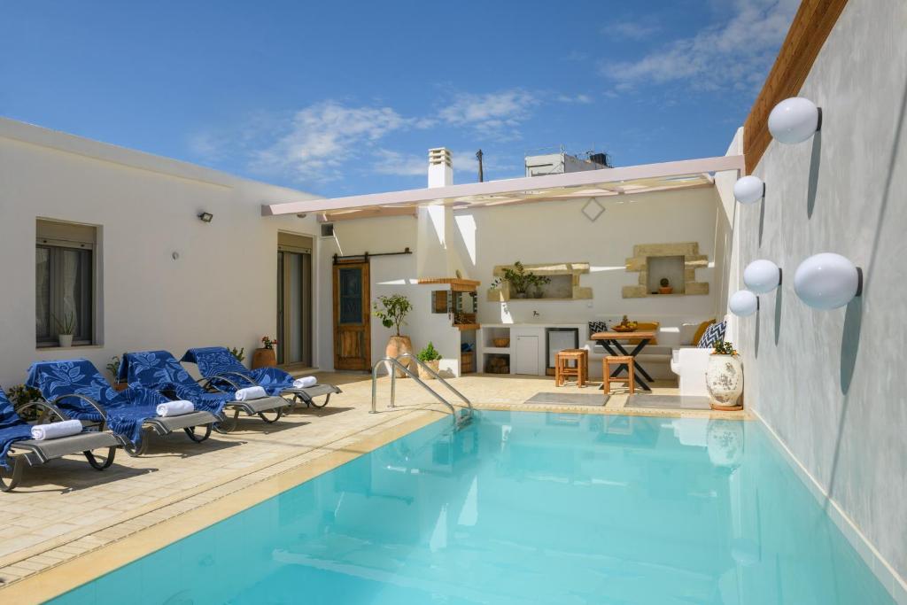 una piscina con sillas azules y una casa en Chrisanthi Elegant Villa en Pitsidia