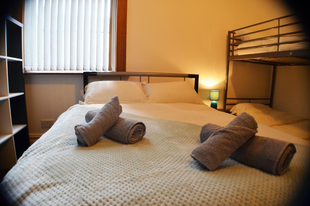 a bedroom with a bed with two pairs of slippers at Old Swan Guest House in Liverpool