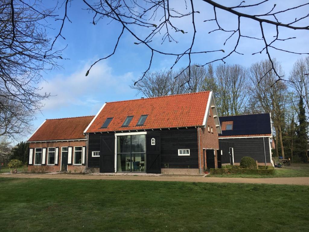 un edificio negro con techo naranja en B&B Boerderij De Vaete - Duurzaam genieten in de zak van Zuid-Beveland en heinkenszand