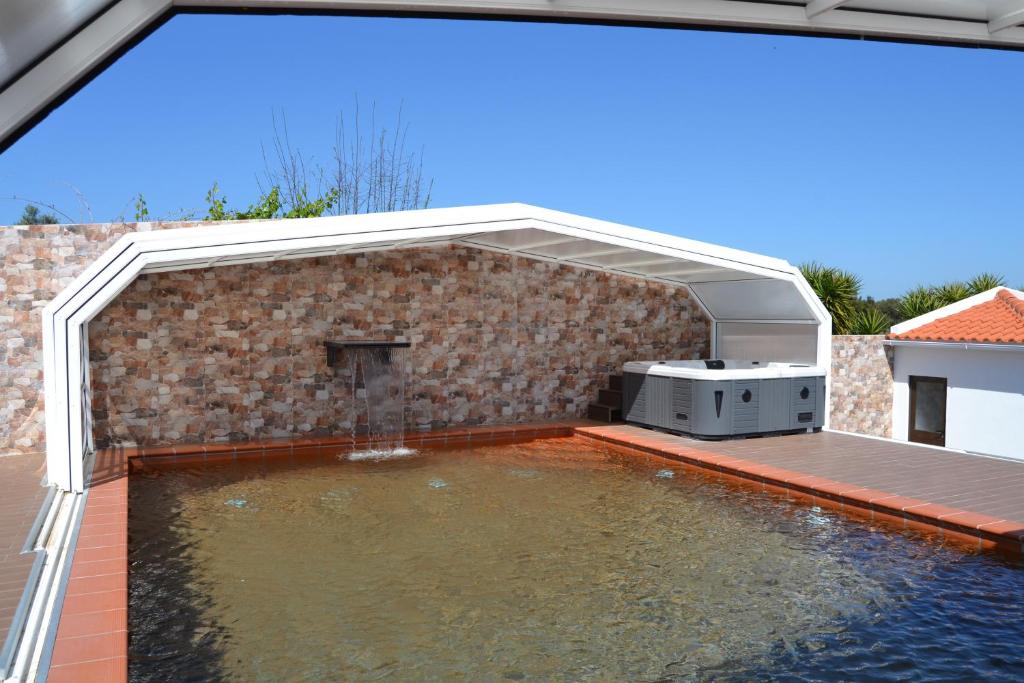 a swimming pool with a barbecue grill on a patio at Fazenda do Medronhal in Montemor-o-Novo