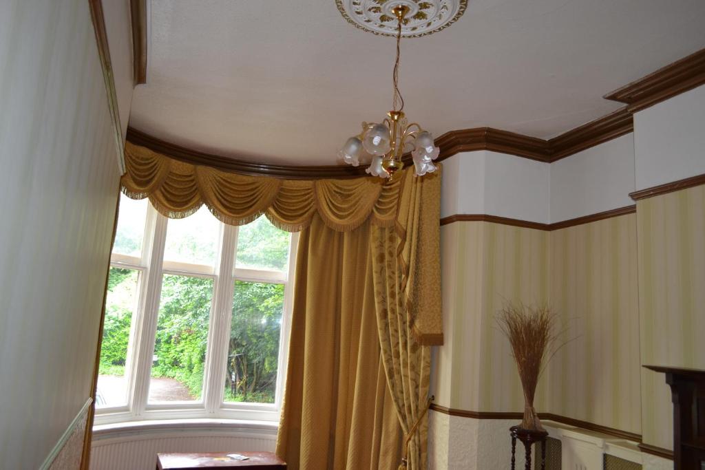 a room with a window with a curtain and a chandelier at Croft Hotel in Leicester