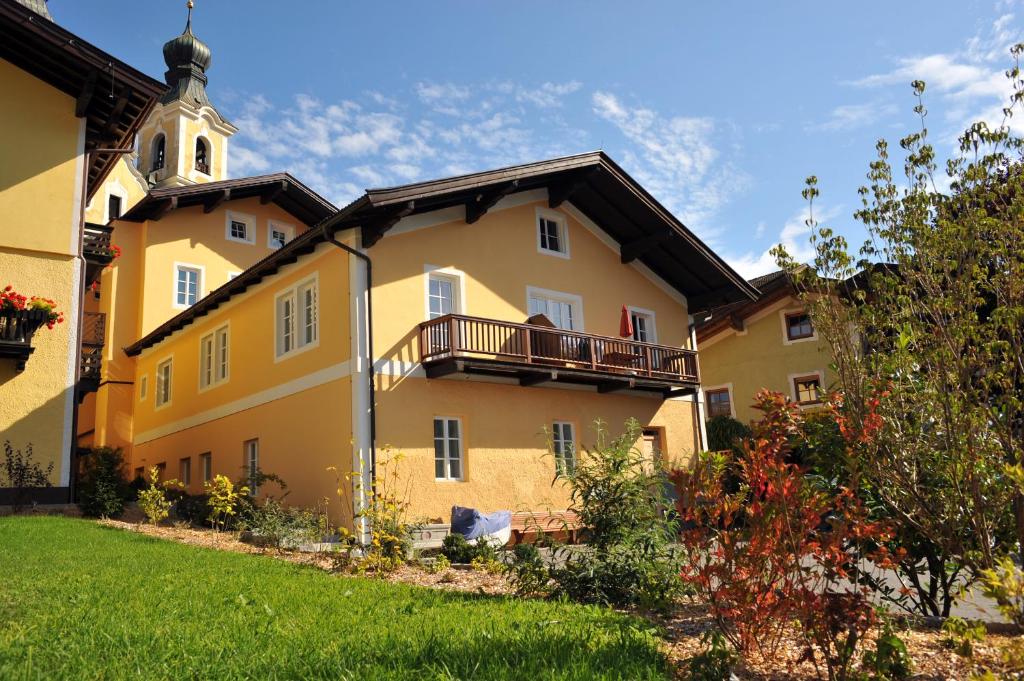 un edificio giallo con una torre dell'orologio in un cortile di Appartements Altes Gericht a Hopfgarten im Brixental