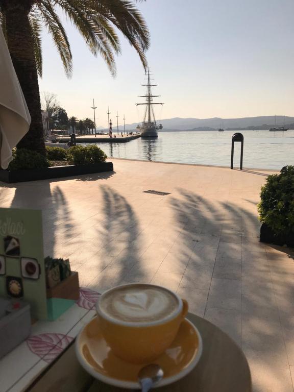 una tazza di caffè seduta su un tavolo accanto all'acqua di Apartment S&T a Tivat