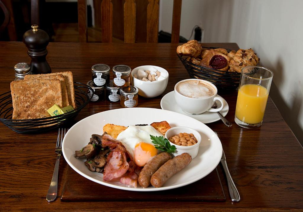 a plate of breakfast food on a wooden table at The Jug And Bottle in Heswall