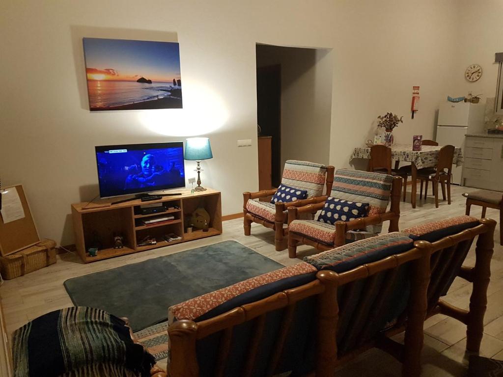 a living room with a flat screen tv and chairs at Our relaxing holiday home in Mosteiros