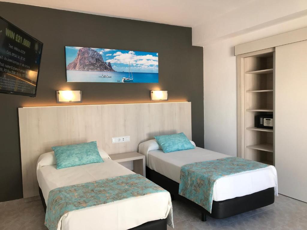 Zimmer mit 2 Betten und einem TV an der Wand in der Unterkunft Hostal Cervantes in Sant Antoni de Portmany