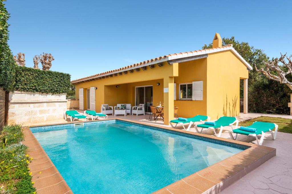 a swimming pool with chairs and a house at Villa Aries in Cala en Forcat