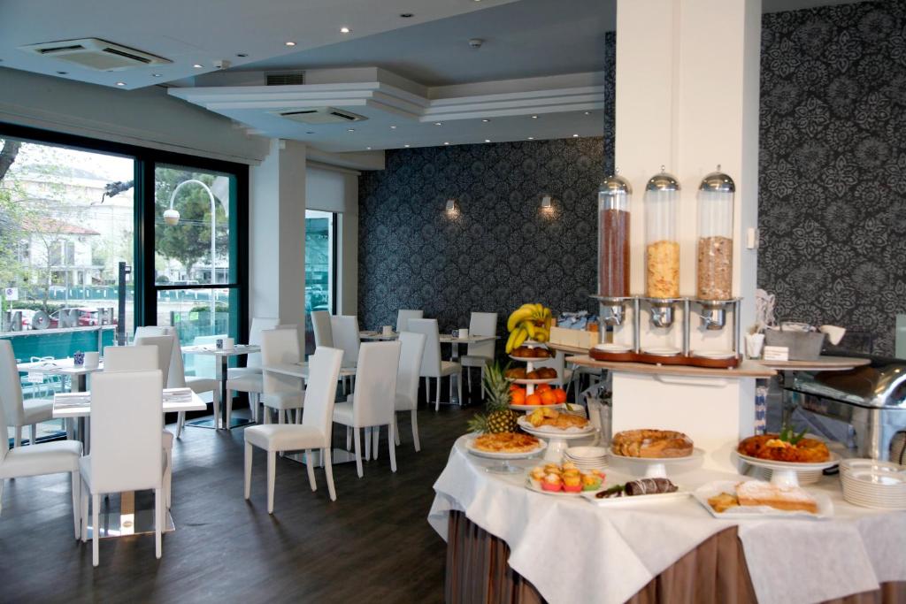 un restaurante con mesas y sillas con comida. en Hotel Montecarlo - Vista Mare con Piscina & Area Fitness, en Riccione