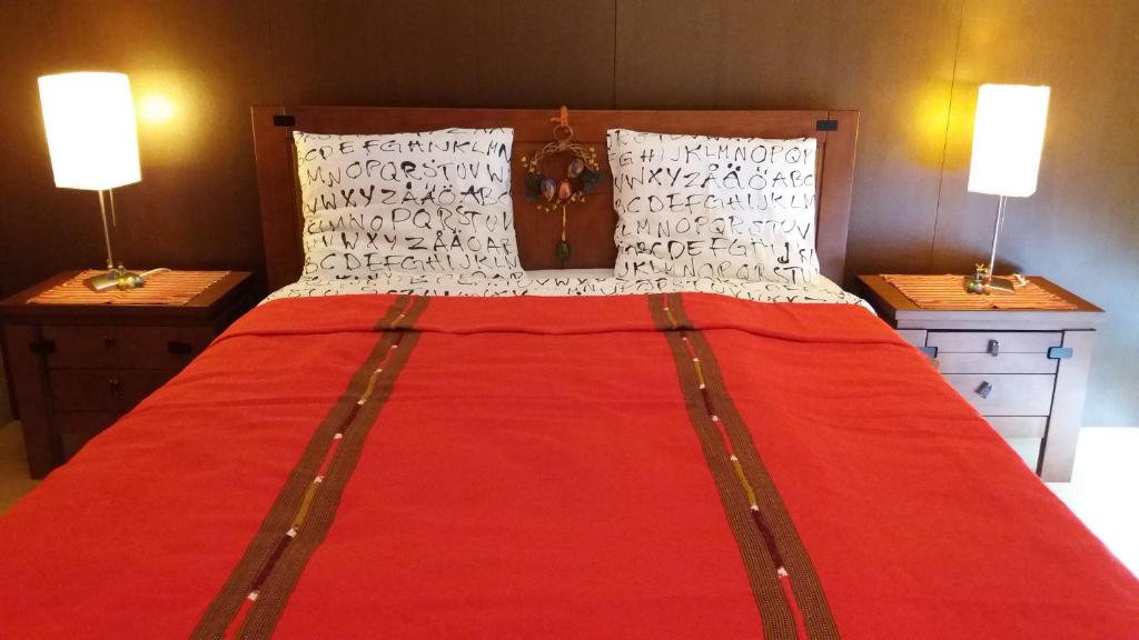 een groot rood bed met twee lampen op twee tafels bij Casa do Mar in Costa Nova