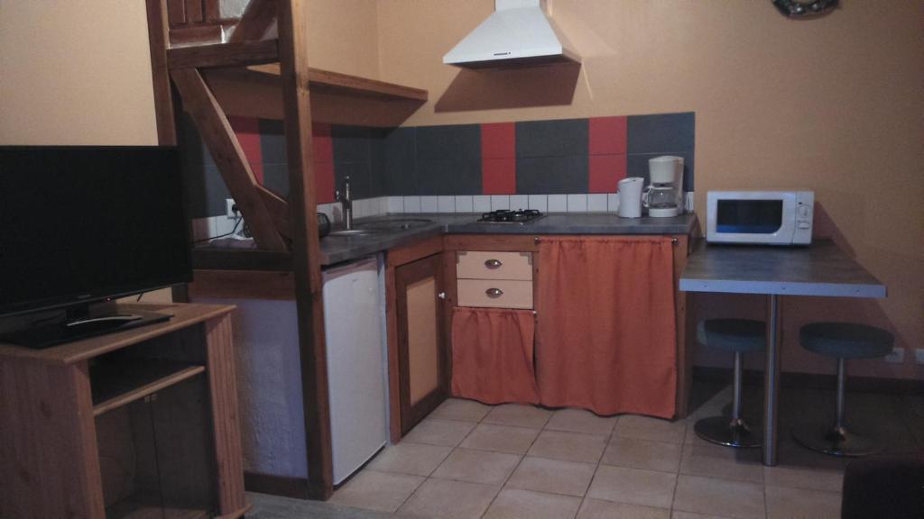 a small kitchen with a sink and a desk with a microwave at suite familiale 2 chambre in Saint-Ouen-les-Vignes