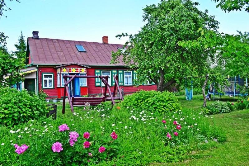 a red house with flowers in front of it at Agroturystyka INKA in Hajnówka