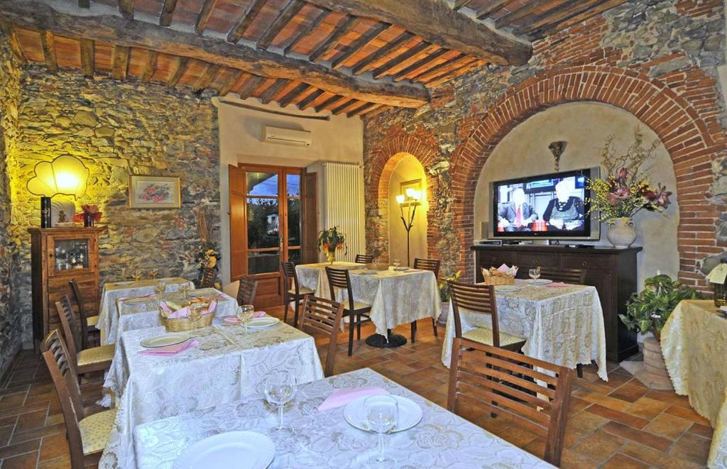 a dining room with tables and chairs and a television at Le Ginestre B & B in Massarosa