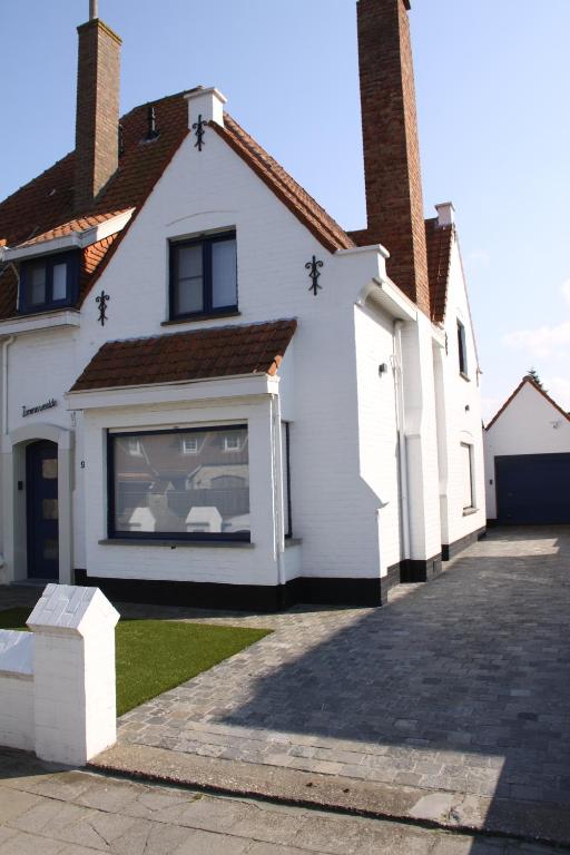 une maison blanche avec une grande fenêtre latérale dans l'établissement Villa Zonneweelde, au Coq