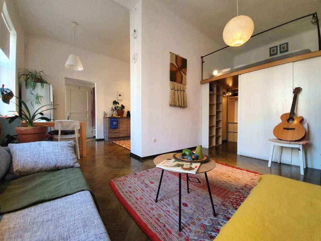 a living room with a couch and a table and a guitar at Cosy Ljubljana Loft in Ljubljana