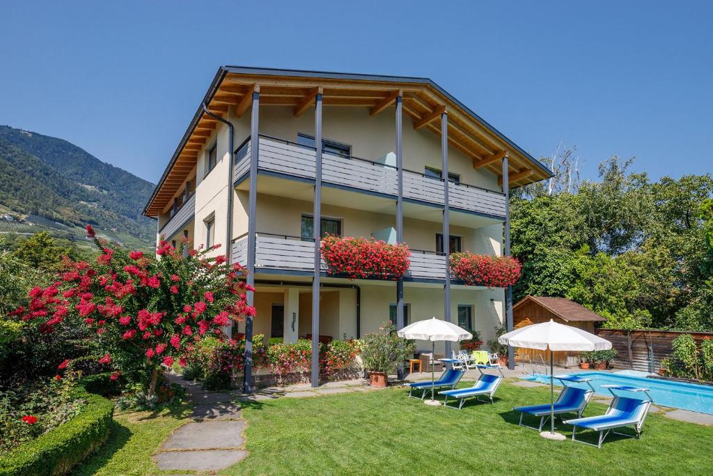 a building with chairs and a swimming pool in front of it at Garni Raffein in Lana