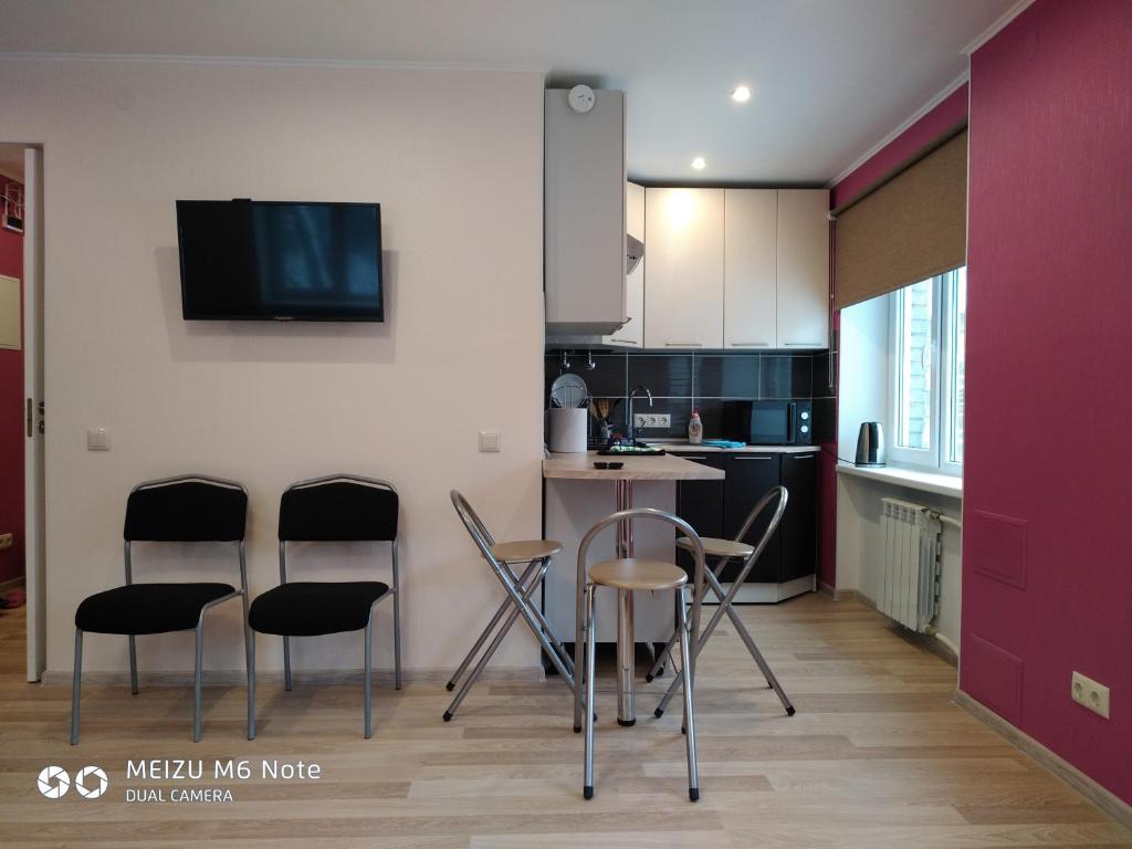 uma cozinha com cadeiras, uma mesa e uma televisão em Sparta Apartments Malmi em Narva