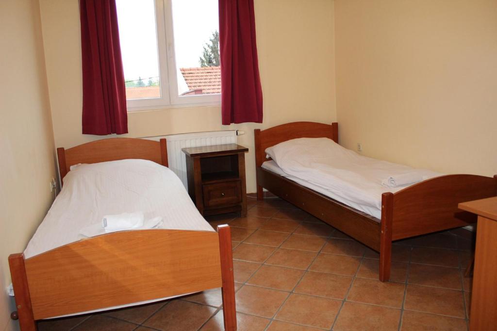 two beds in a room with a window at Prenoćište "Magnus" in Slavonski Brod