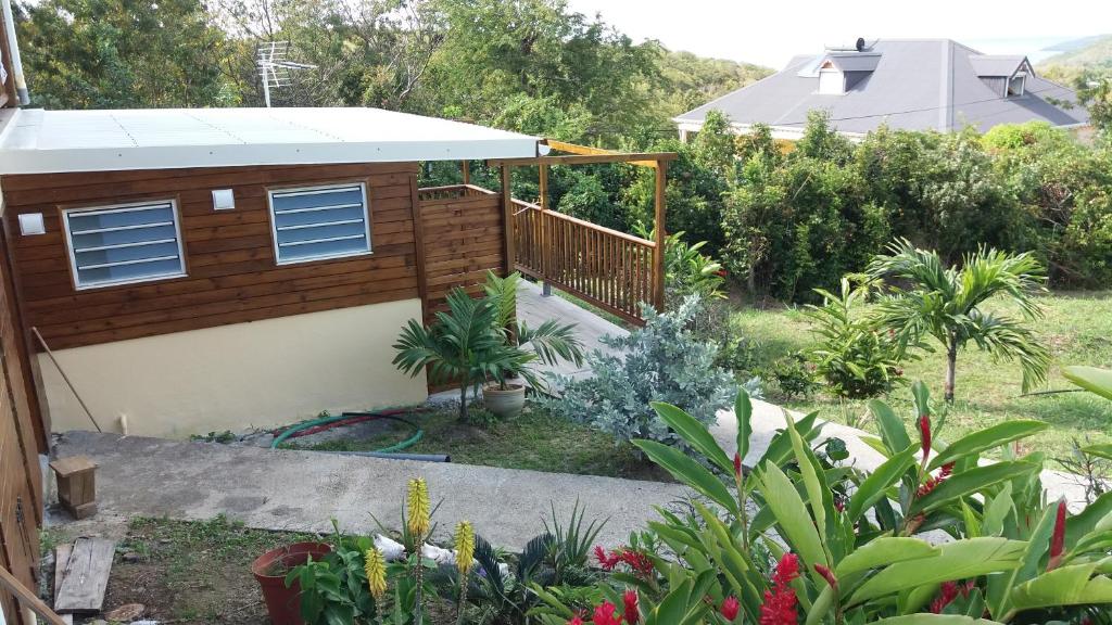 ein kleines Haus mit einer Terrasse im Garten in der Unterkunft Gîte Bananier in Bouillante