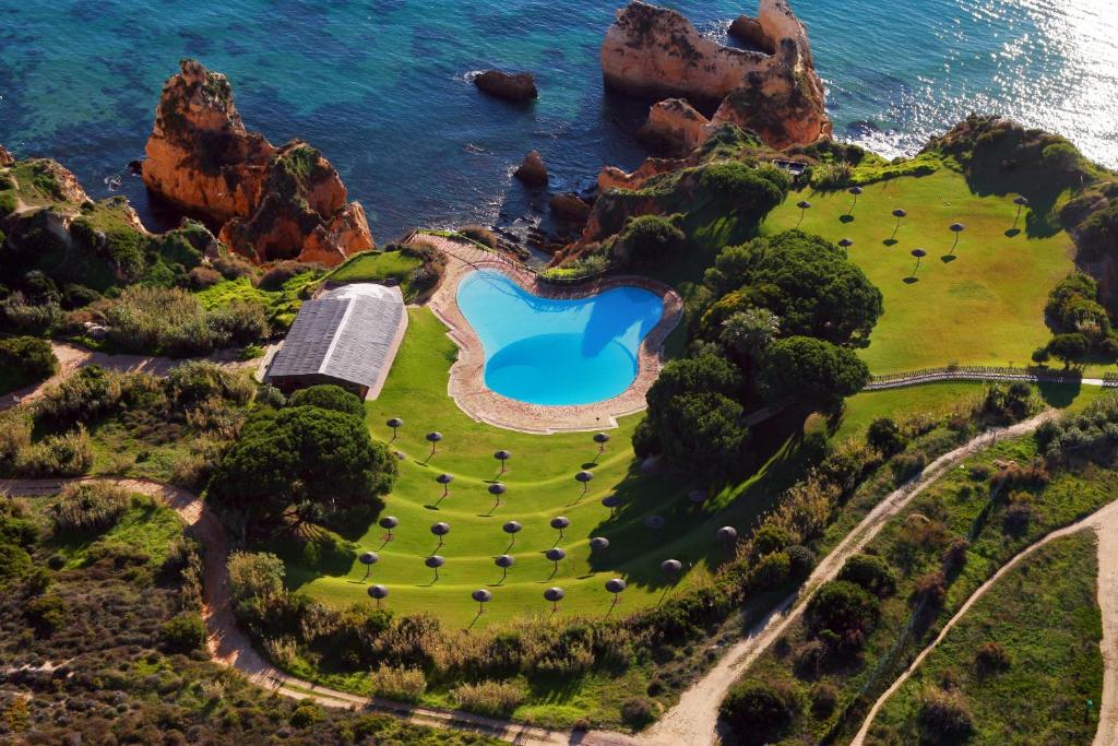 an island with a swimming pool on the ocean at Aldeamento Turistico da Prainha in Alvor