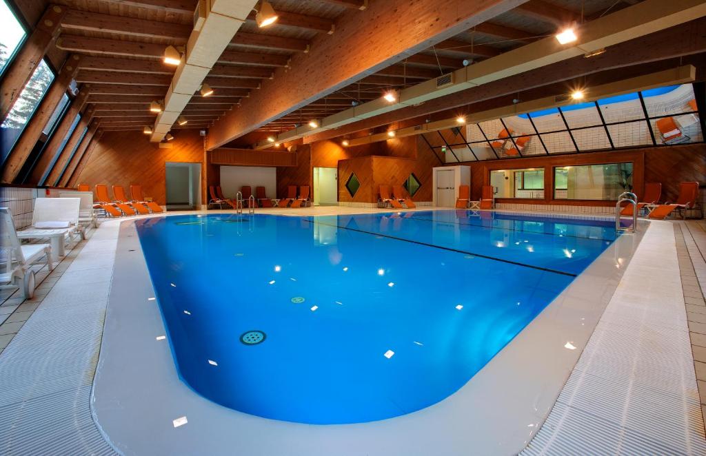 a large swimming pool with blue water in a building at Grand Hotel Presolana in Castione della Presolana