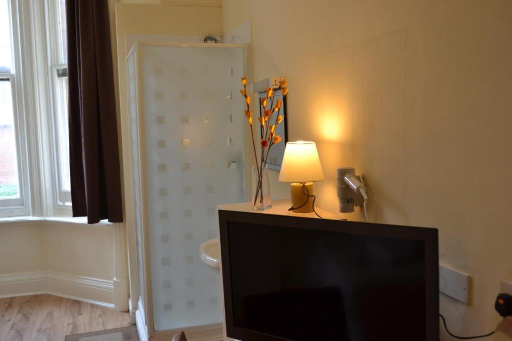 a television in a living room with a lamp and a bathroom at Croft Hotel in Leicester