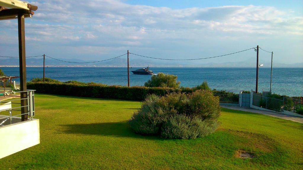 a boat in the ocean with a house and a bush at Beautiful house by the sea,Loutraki Skaloma. in Loutraki