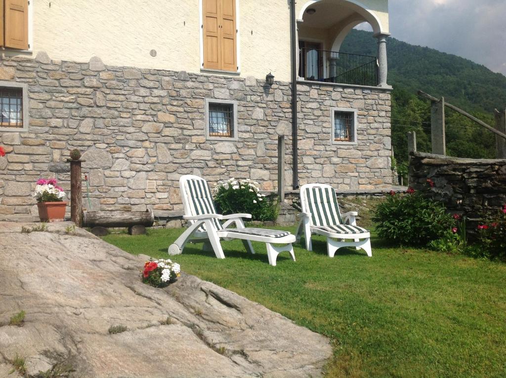 two white chairs sitting in front of a stone building at Casa Brencio in Masera