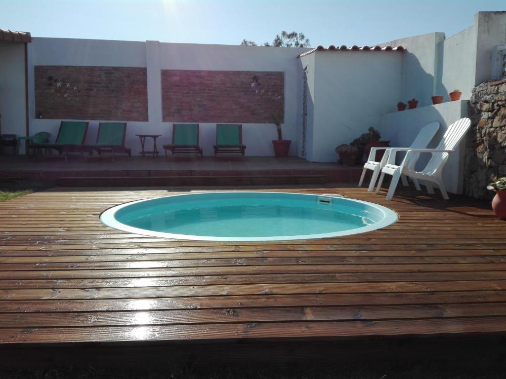 a small swimming pool on a wooden deck with chairs at Casa Vitorino's in Vale de Maceira