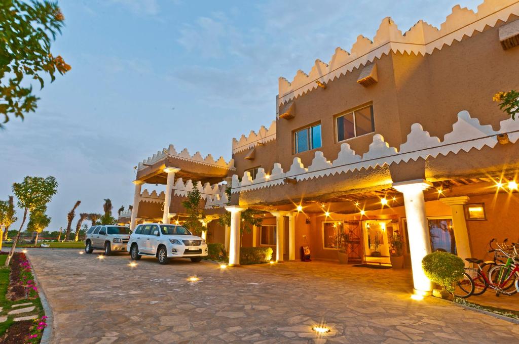 a large building with cars parked in front of it at Al Malfa Resort in Unayzah