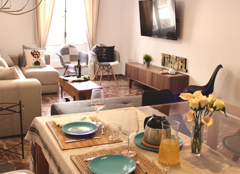 una sala de estar con una mesa con copas de vino y flores en GATU PREMIUM Villa Aramburu, en El Puerto de Santa María
