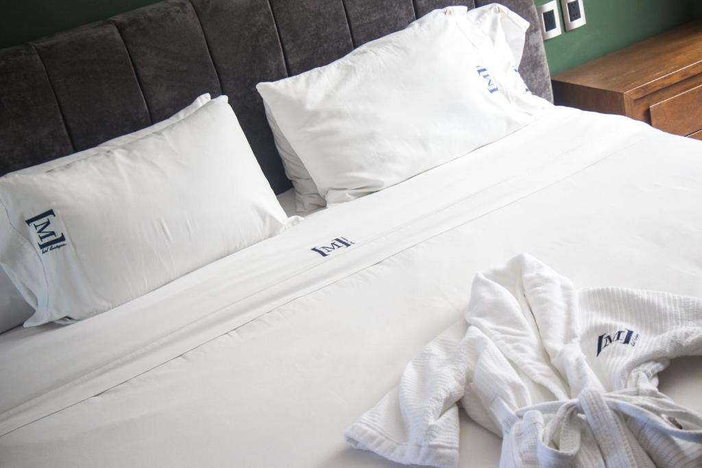 a bed with white sheets and pillows on it at Maja Hotel Boutique in Morelia
