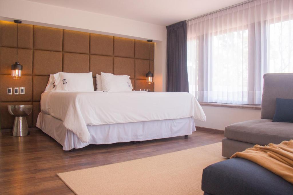 a bedroom with a large white bed and a couch at Maja Hotel Boutique in Morelia