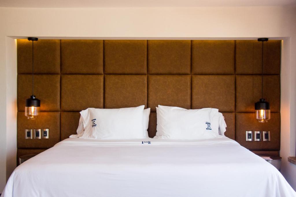 a large bed with white sheets and pillows at Maja Hotel Boutique in Morelia