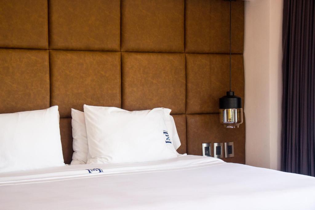 a bed with white pillows and a brown headboard at Maja Hotel Boutique in Morelia
