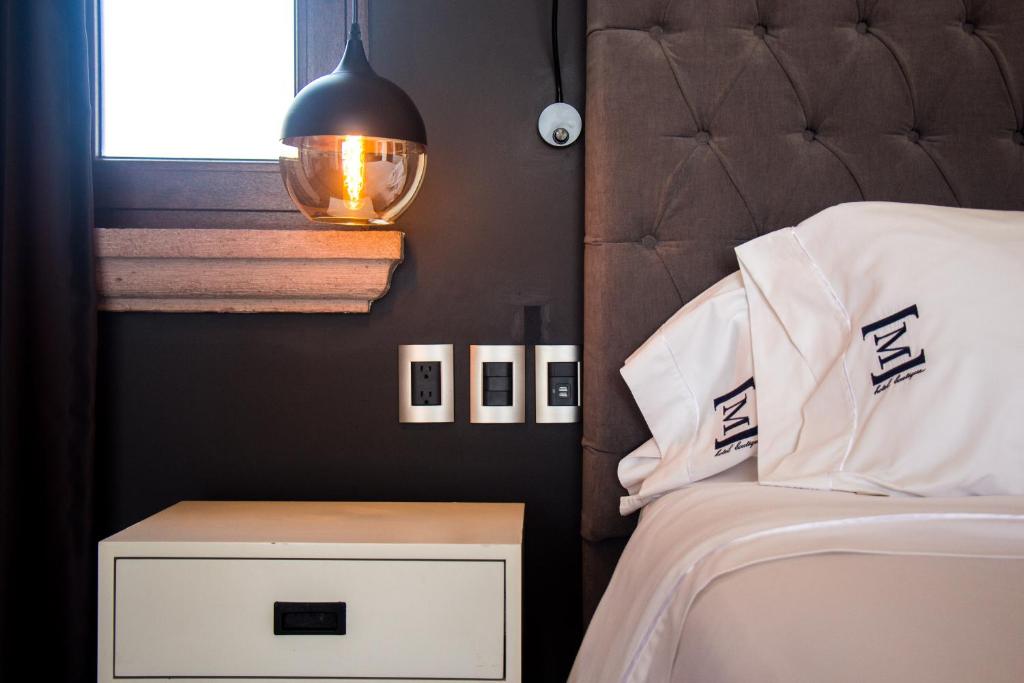 a bedroom with a bed and a nightstand and a lamp at Maja Hotel Boutique in Morelia