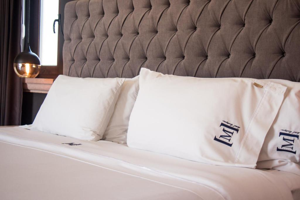 a bed with white sheets and pillows on it at Maja Hotel Boutique in Morelia