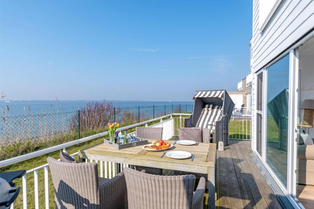 a balcony with a table and chairs and the ocean at SchleiZeit in Olpenitz
