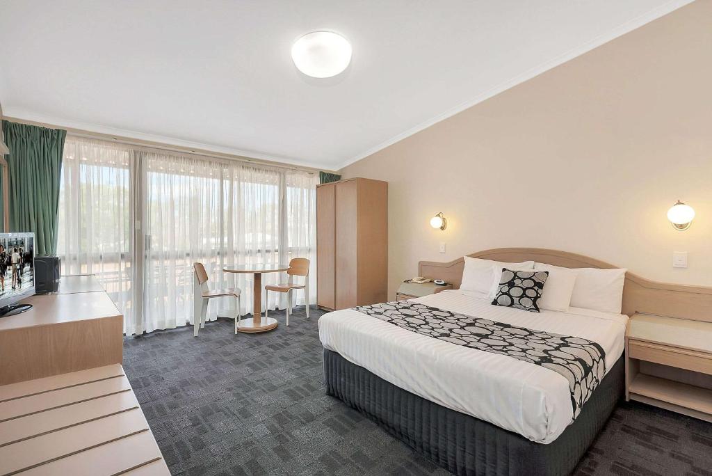 
a hotel room with a bed and a dresser at Econo Lodge Toowoomba Motel & Events Centre in Toowoomba
