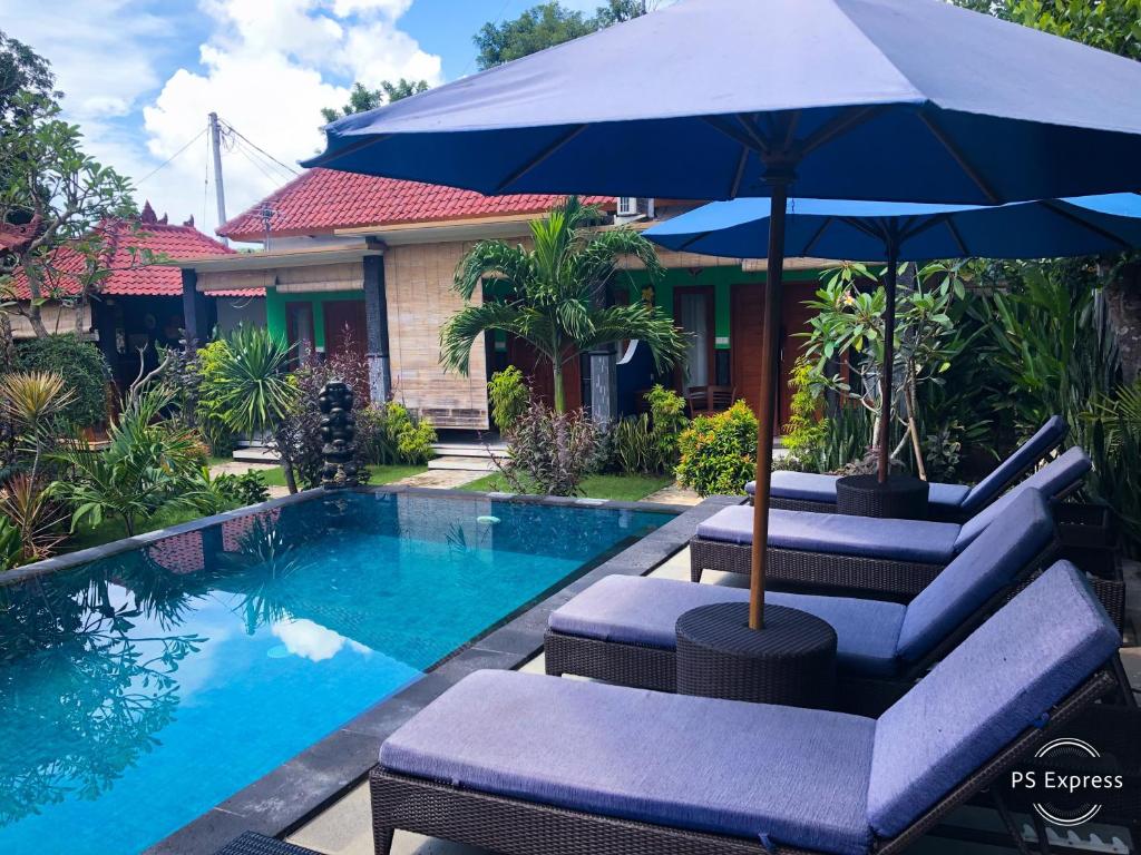 einem Pool mit Stühlen und einem Sonnenschirm neben einem Haus in der Unterkunft D'Waktu in House in Nusa Lembongan