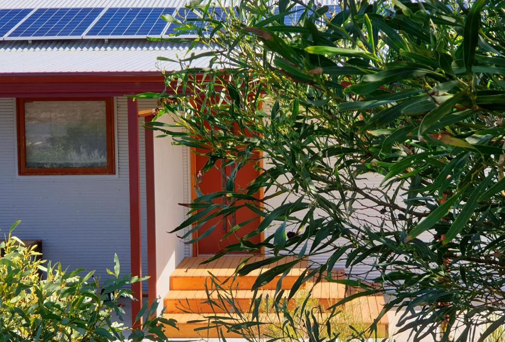 una casa con una puerta roja y paneles solares en ella en Samphire: Coorong Accommodation, en Meningie